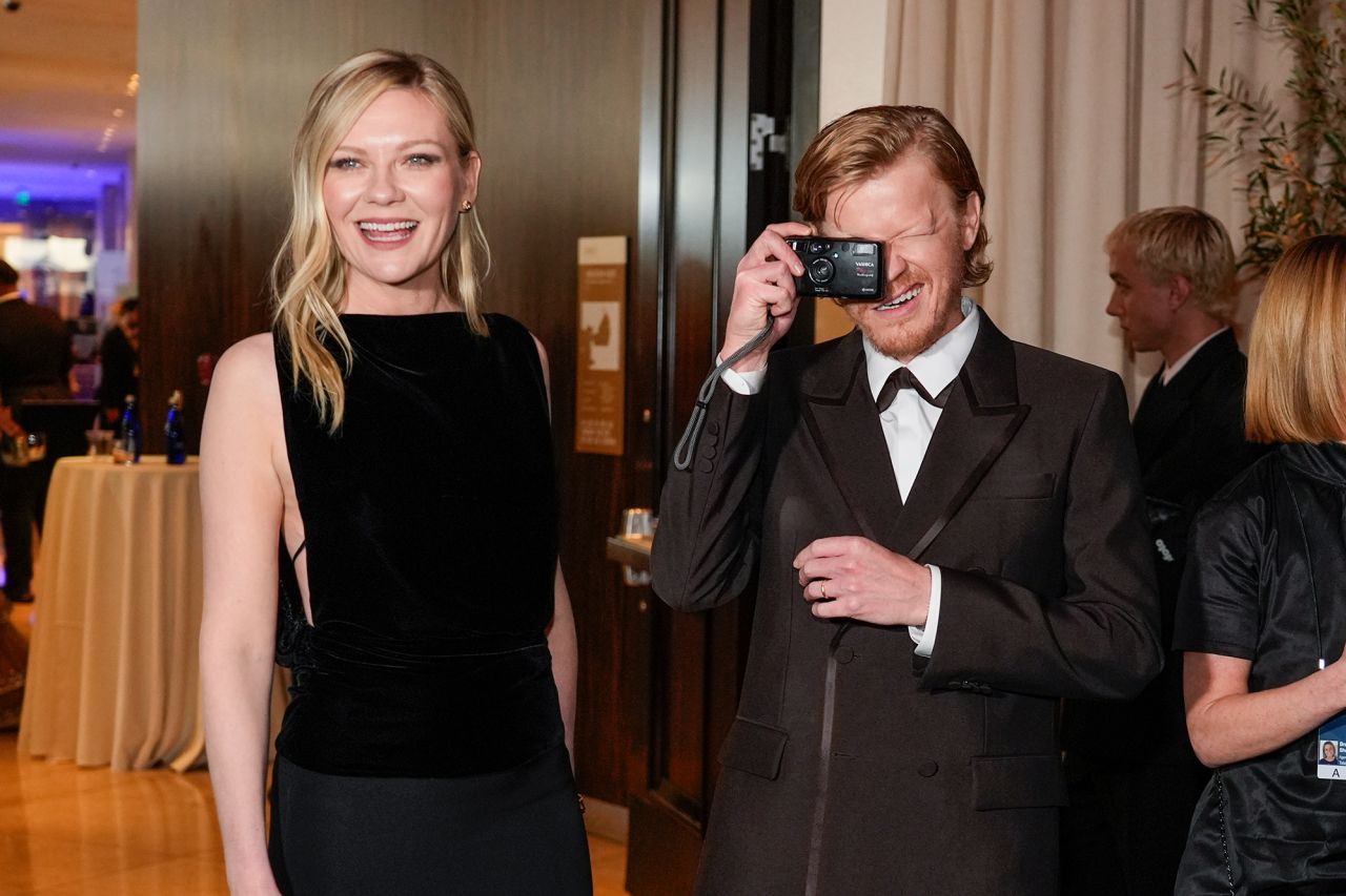 Jesse Plemons takes a photo while standing next to Kirsten Dunst.