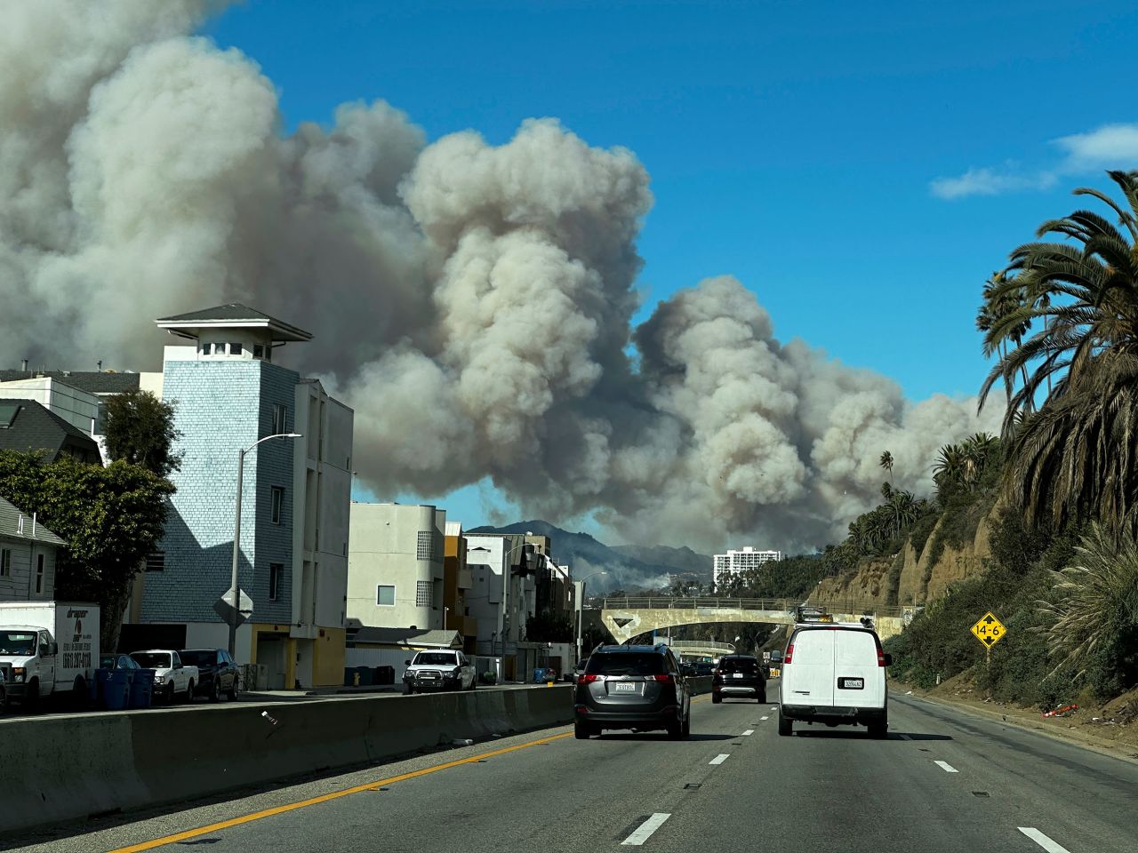 Heavy smoke from a brush fire in the Pacific Palisades rises over the Pacific Coast Highway in Santa Monica, California, on Tuesday, January 7.