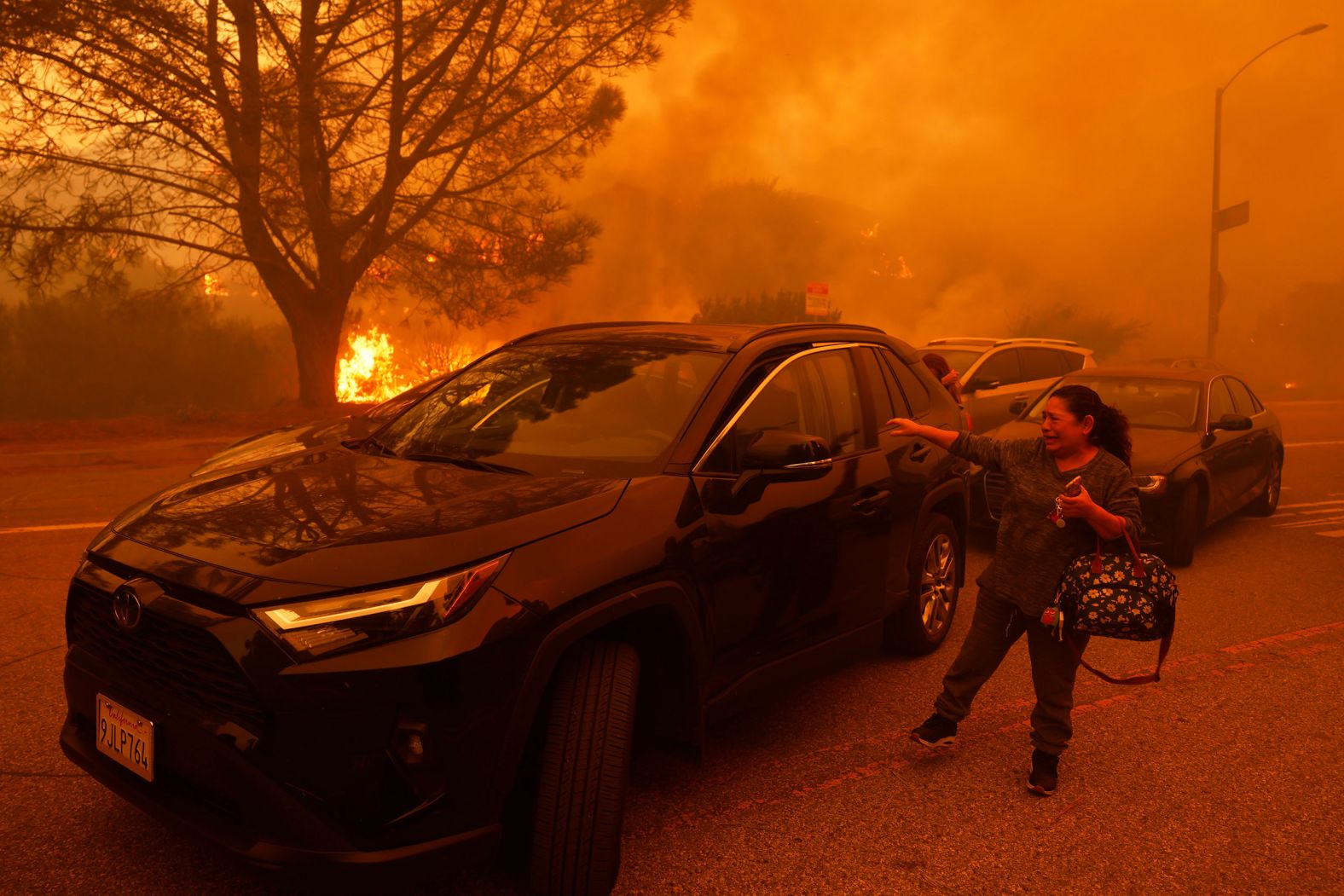 A woman cries as a fire advances in Pacific Palisades.