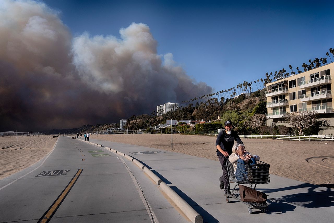 Jerome Krausse pushes his mother-in-law in a shopping cart as they evacuate from their home in Santa Monica, California, on January 7.