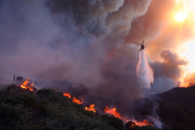 Water is dropped over Pacific Palisades by a firefighting helicopter.