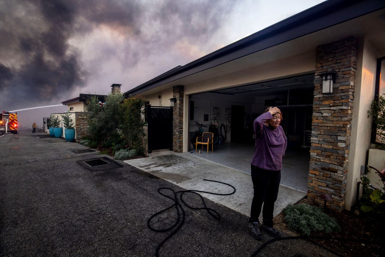 A resident stands in front of a garage as fire crews fight the Palisades Fire nearby in the Pacific Palisades neighborhood of Los Angeles on Tuesday.