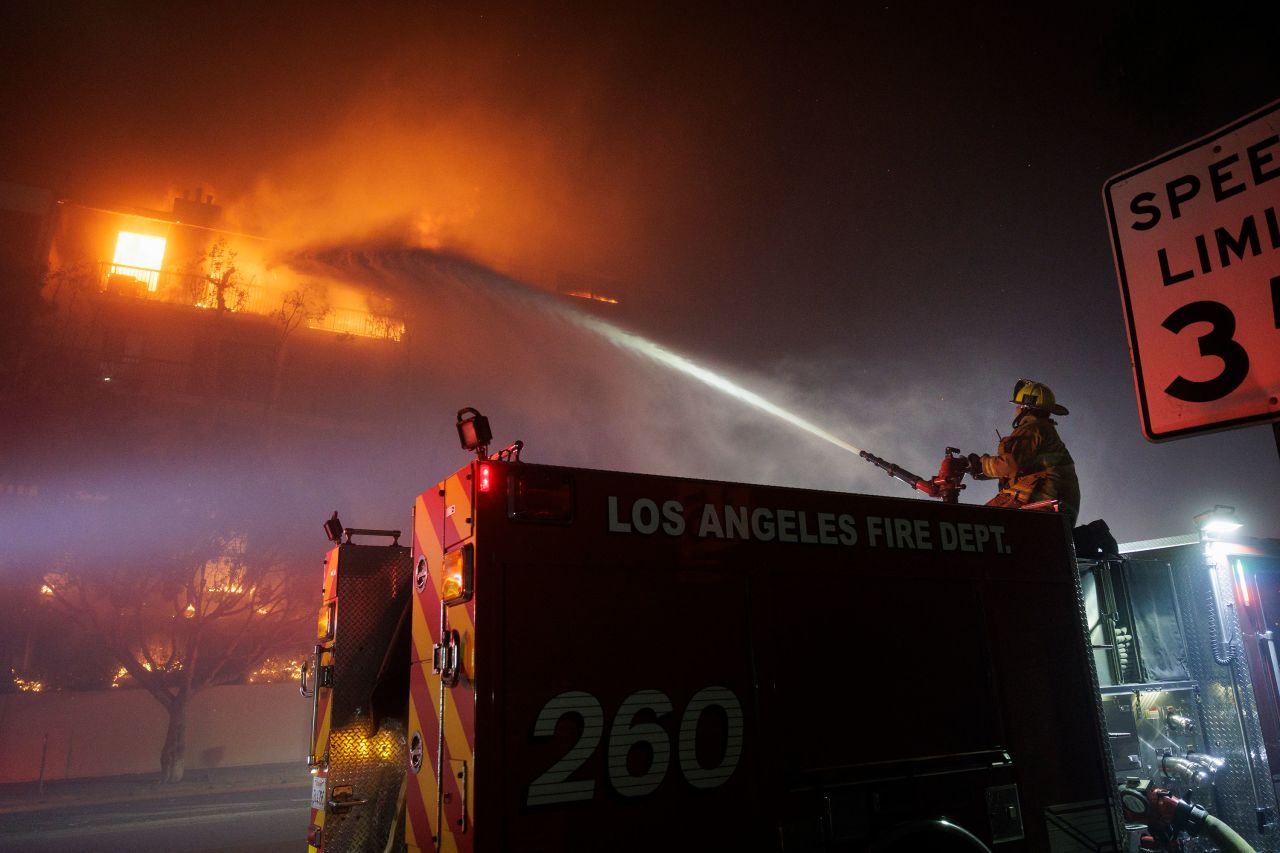 A Los Angeles Fire Department firefighter sprays water on a burning apartment complex caused by the Palisades Fire in the Pacific Palisades neighborhood of Los Angeles on January 7.