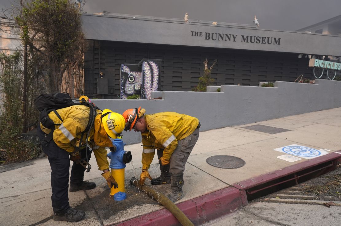 Firefighters work a hydrant in front of the burning Bunny Museum in Altadena on January 8.