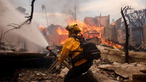 A firefighter battles the Palisades Fire around a burned structure in the Pacific Palisades neighborhood of Los Angeles on Wednesday.