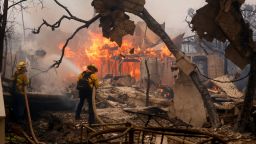 Firefighters battle the Palisades Fire as it burns a structure in the Pacific Palisades neighborhood of Los Angeles, Wednesday, Jan. 8, 2025. (AP Photo/Etienne Laurent)