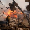 Firefighters battle the Palisades Fire as it burns a structure in the Pacific Palisades neighborhood of Los Angeles, Wednesday, Jan. 8, 2025. (AP Photo/Etienne Laurent)