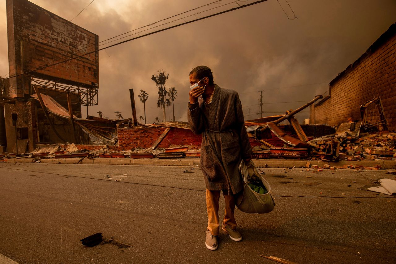 A man walks past a business ravaged by the Eaton Fire on  January 8, in Altadena, California.