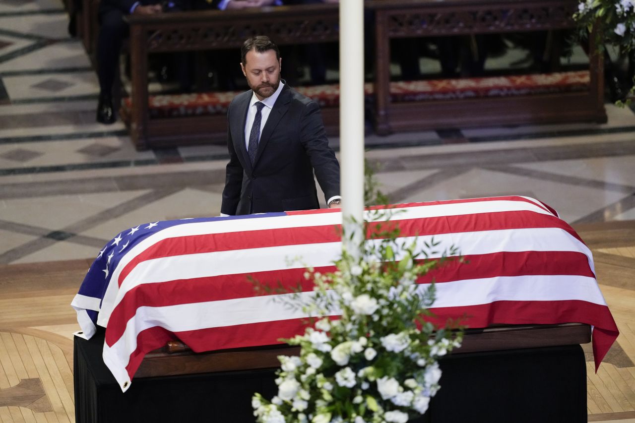 Jason Carter touches his grandfather's casket after speaking at the funeral. <a href="index.php?page=&url=https%3A%2F%2Fwww.cnn.com%2Fpolitics%2Flive-news%2Fjimmy-carter-funeral-01-09-25%23cm5pip5tb001x3b5vahaafxh6">Carter jokingly described his grandfather as “the first millennial”</a> after listing many of his progressive stances.