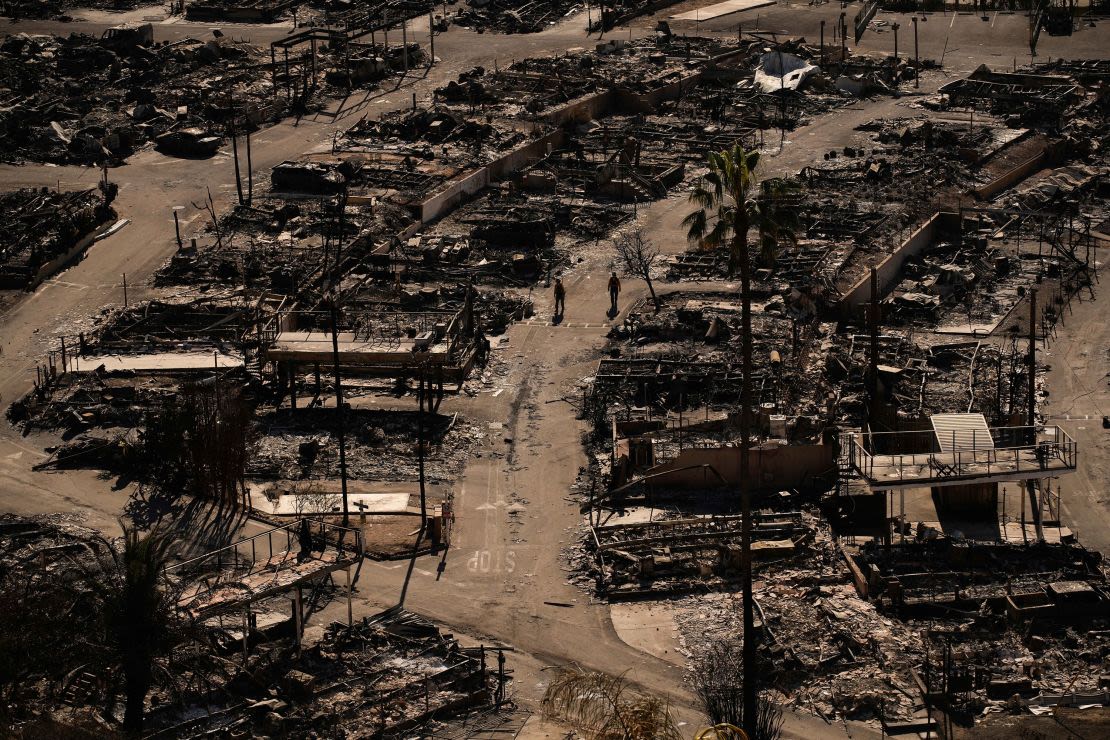 Bomberos caminan a lo largo de una carretera en una comunidad devastada por el fuego en el barrio de Pacific Palisades de Los Ángeles el 13 de enero.