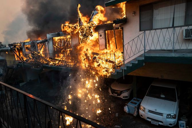 An apartment building lit by the Eaton Fire collapses in Altadena.