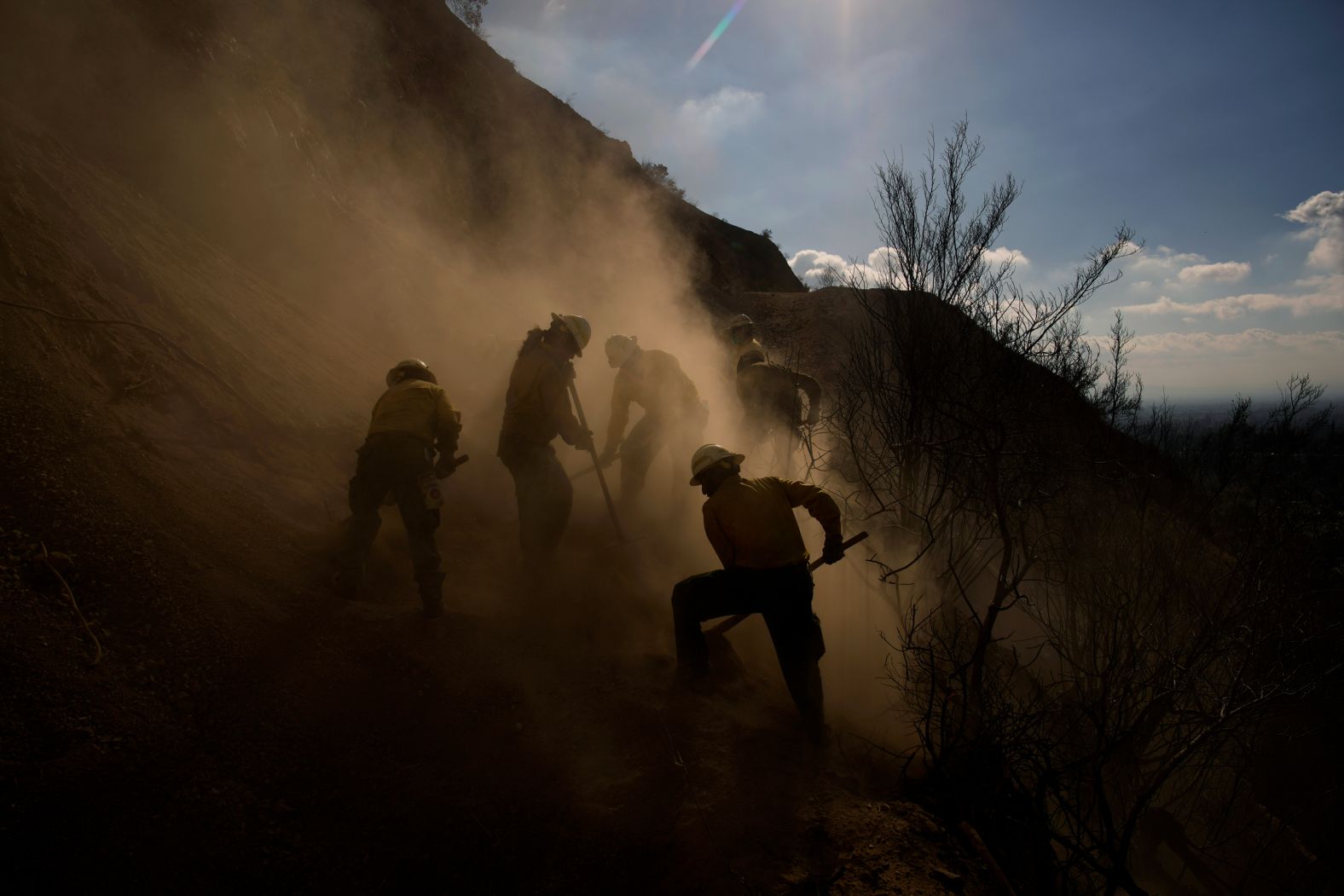 Members of the Navajo Scouts firefighter crew kick up dust as they clear debris from a landslide in Altadena on January 17.