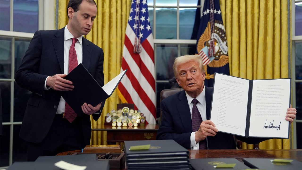President Donald Trump holds up an executive order commuting sentences for people convicted of Jan. 6 offenses in the Oval Office of the White House, Monday, Jan. 20, 2025, in Washington. (AP Photo/Evan Vucci)