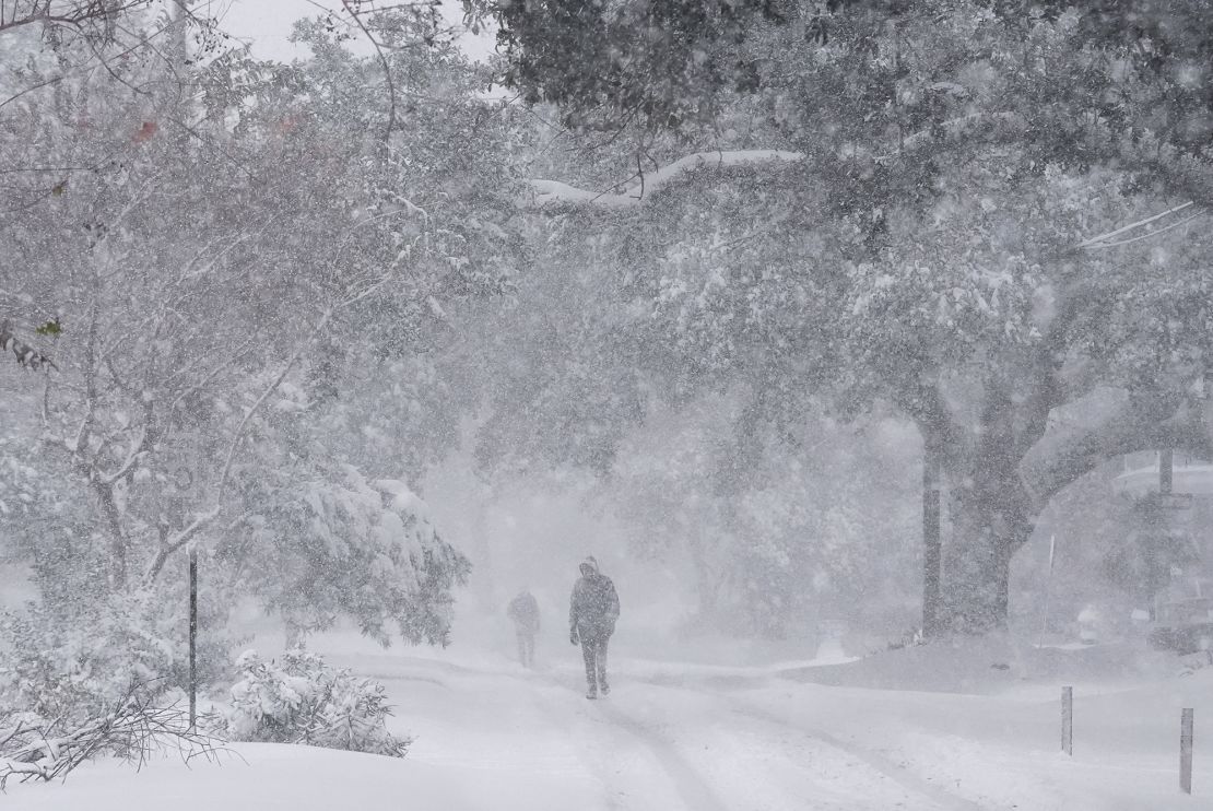 People walk as snow falls in New Orleans on Tuesday.