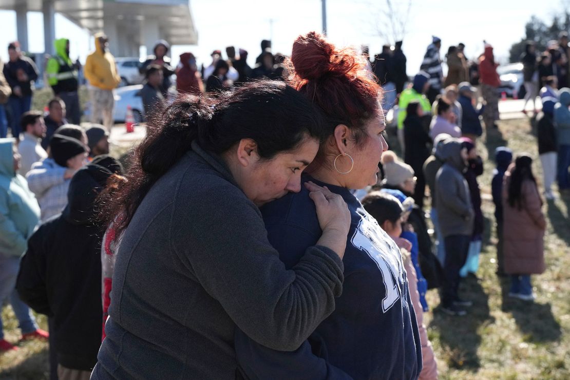 People wait as school buses arrive at a unification site following Wednesday's shooting.