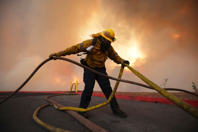 A firefighter sets out hoses to fight the Hughes Fire.