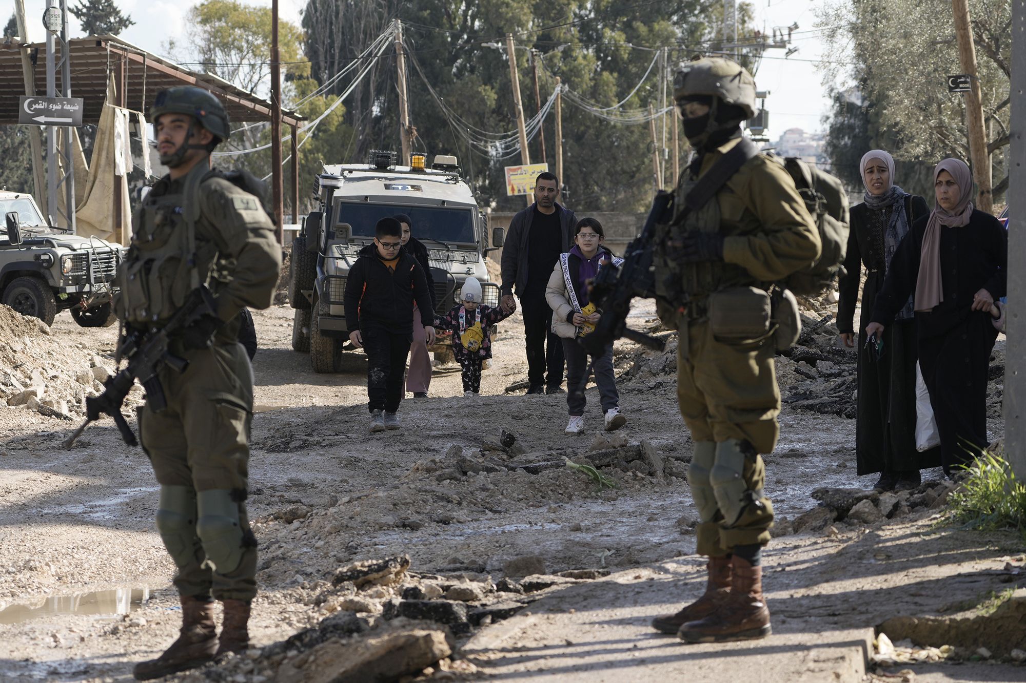 israeli soldiers stand guard as palestinians displaced by an israeli military operation evacuate from the jenin refugee camp in the west bank