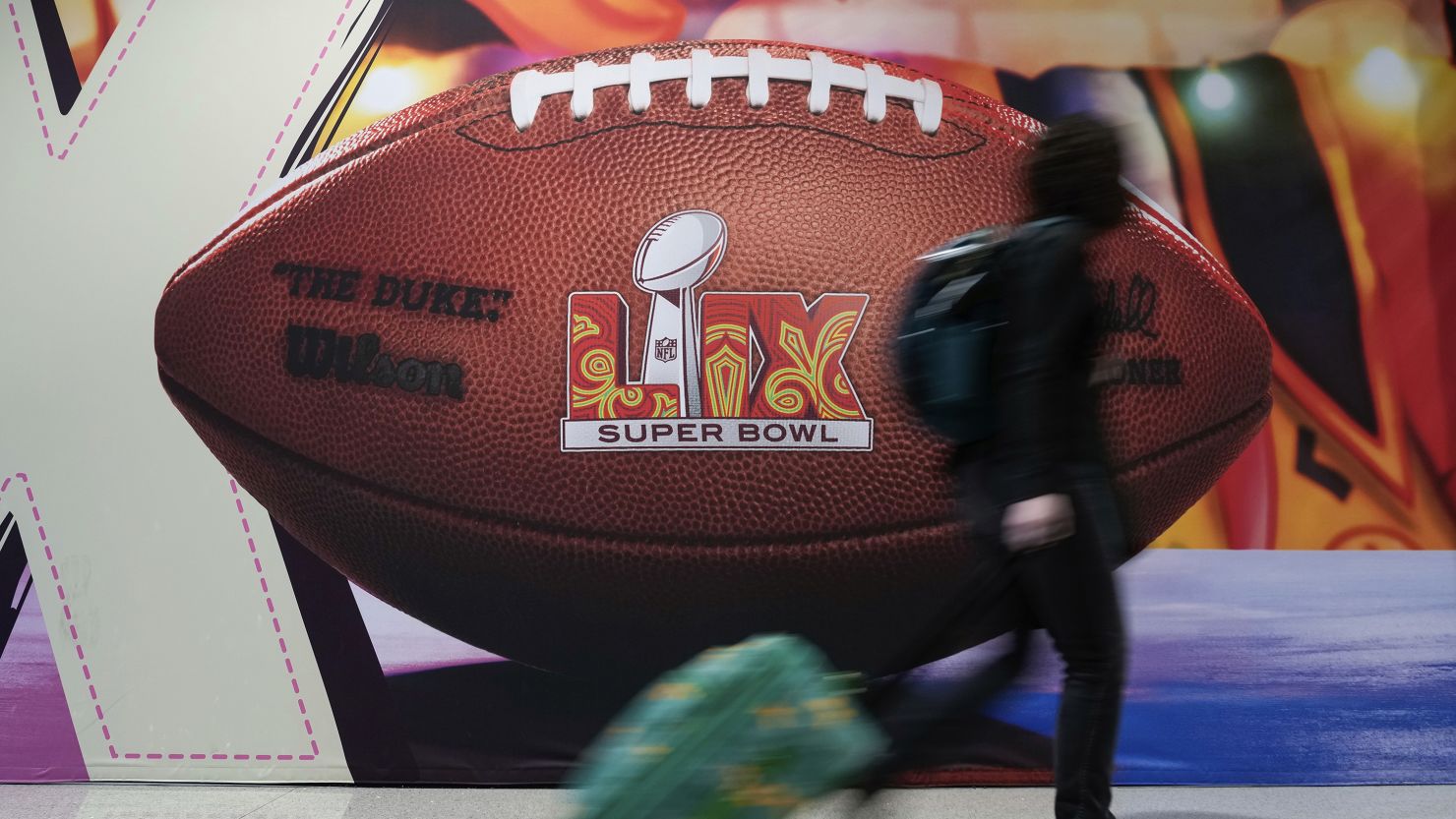 A traveler walks past a Super Bowl advertisement at Louis Armstrong New Orleans International Airport.