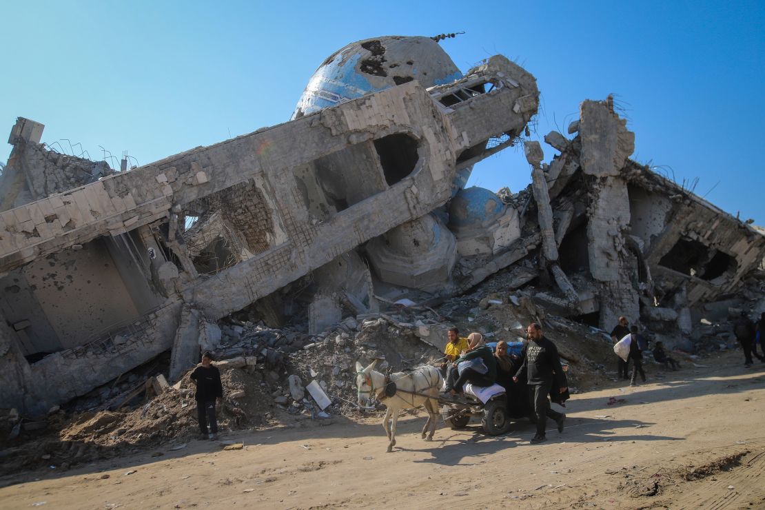 Uma família cavalga em um carrinho puxado a cavalo, passando por uma mesquita destruída em Beit Lahia, Gaza, em 29 de janeiro.