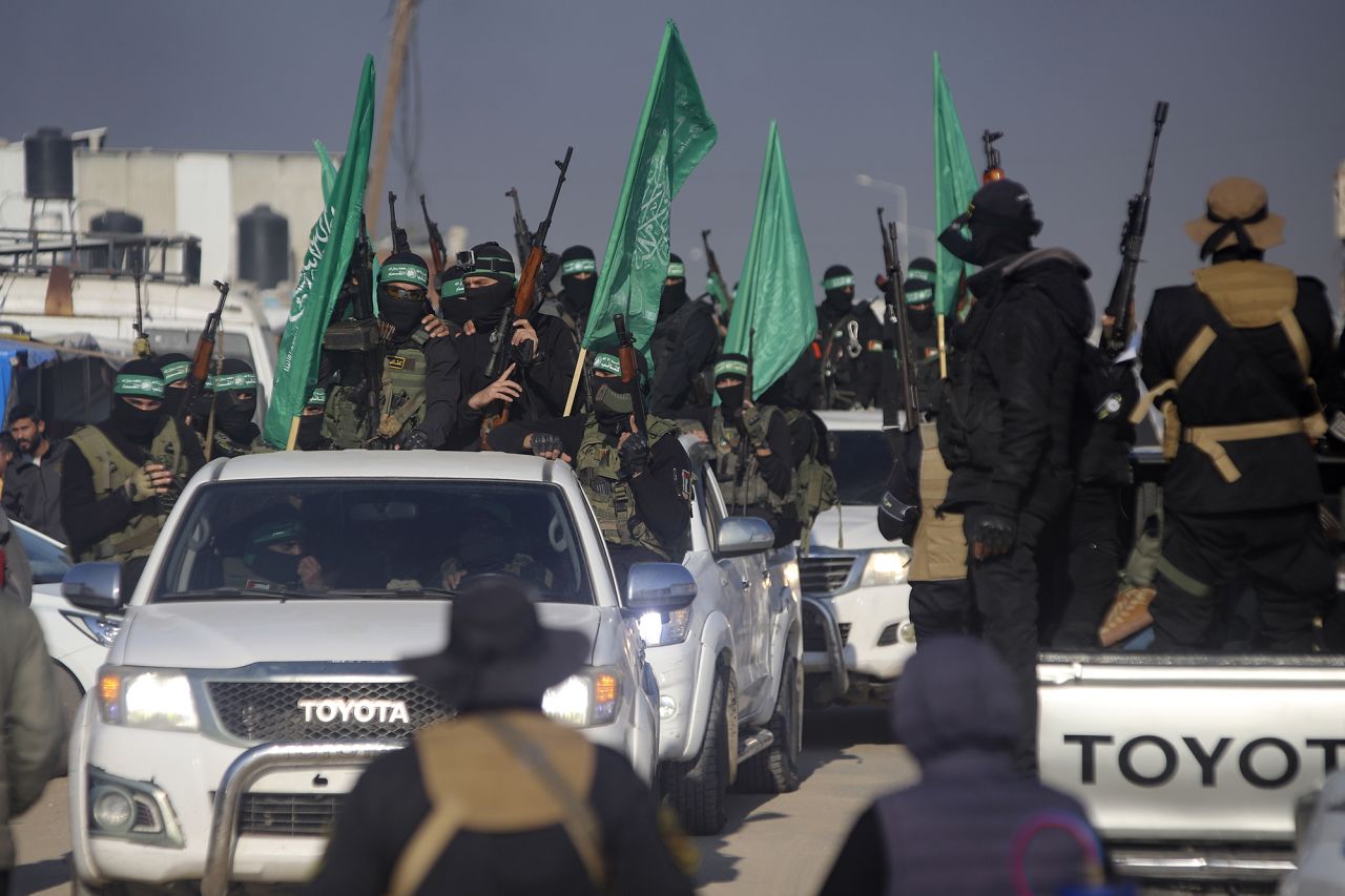 A crowd greets Islamic Jihad and Hamas fighters as they arrive for the hand-over of Israeli and Thai hostages to the Red Cross in Khan Younis, Gaza, on Thursday.