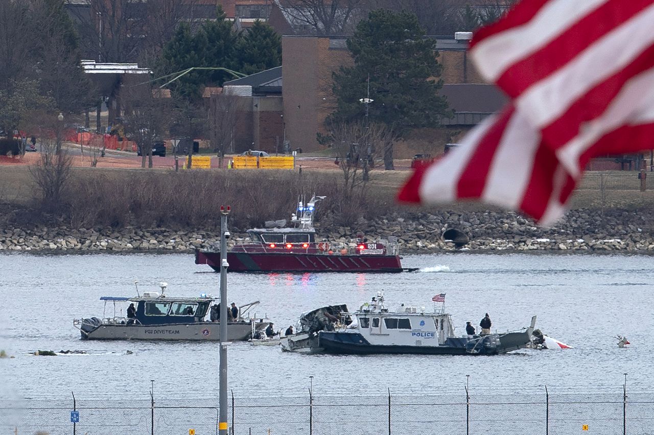 A diving team and police boat are seen around the wreckage site in the Potomac River near Ronald Reagan Washington National Airport, on Thursday.