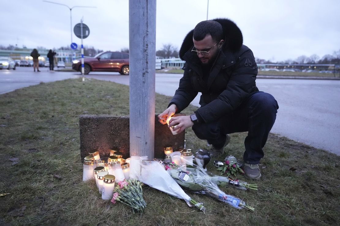 A man lights a candle at a provisional memorial near Campus in Örebro on Wednesday.