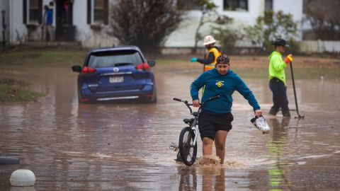 Siquoia Jackson, of Huntington, pulls a bike through the floodwater while trying to travel through the Enslow Park neighborhood on Thursday, Feb. 6, 2025, in Huntington, W.Va.  (Ryan Fischer/The Herald-Dispatch via AP)