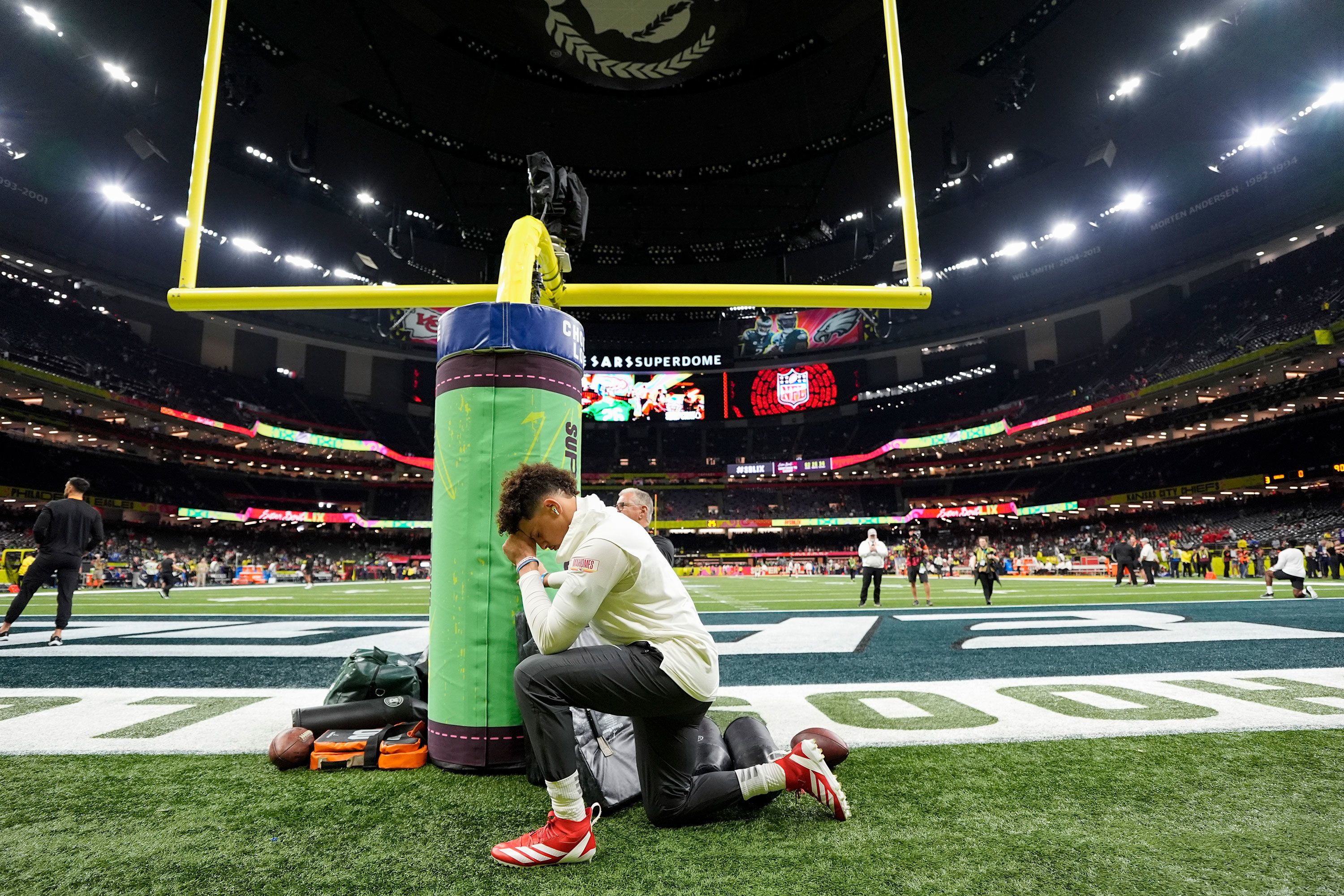 Mahomes kneels on the field during pregame warmups.