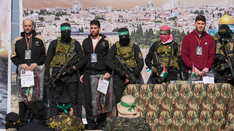 Israeli hostages Iair Horn, 46, left, Sagui Dekel Chen, 36, center left, and Alexander Troufanov, 29, right, are escorted by Hamas and islamic Jihad fighters as they are handed over to the Red Cross in Khan Younis, Gaza Strip, Saturday, Feb. 15, 2025. (AP Photo/Abdel Kareem Hana)