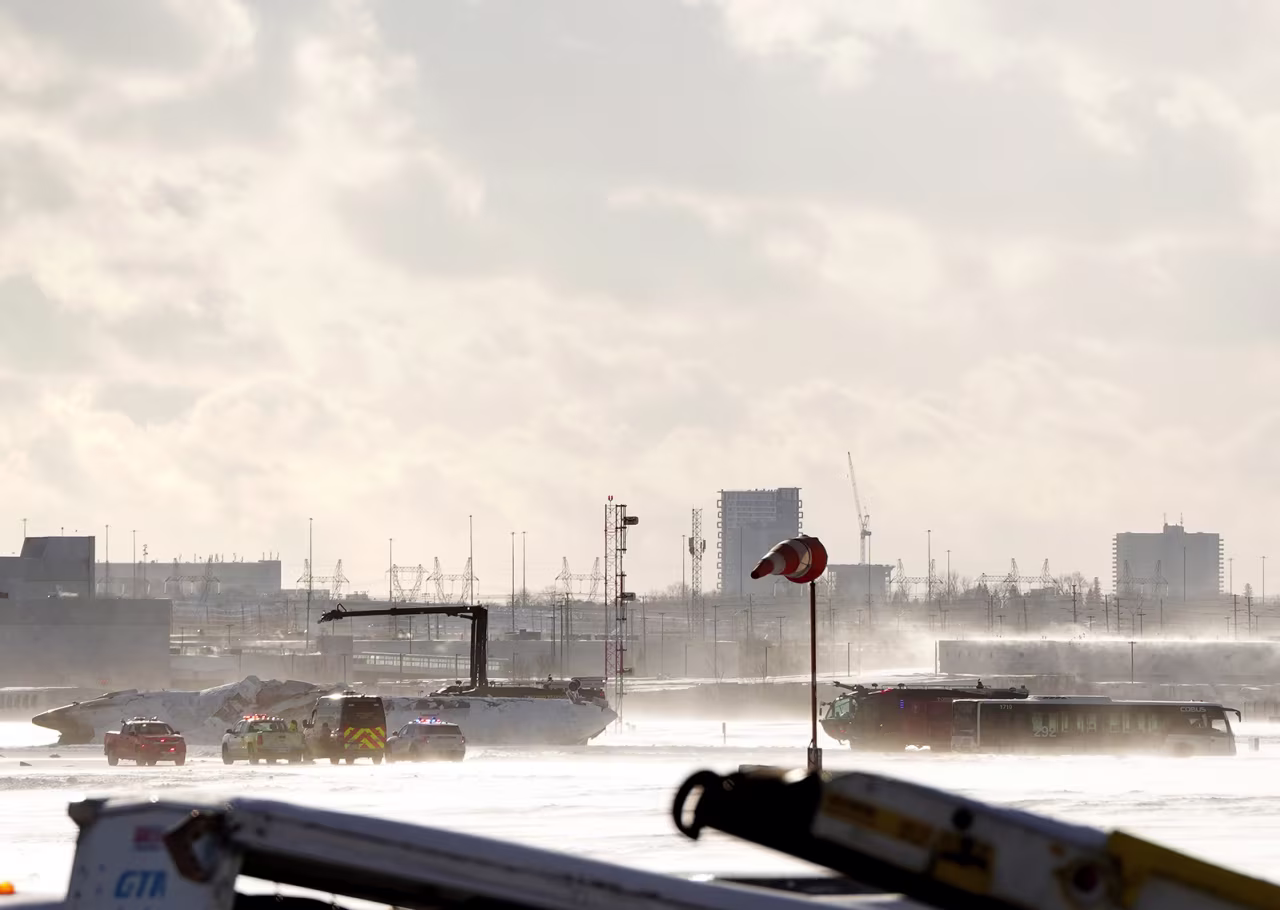 Crews work around an upside down Delta Air Lines plane at Pearson International Airport, in Toronto, on Monday.