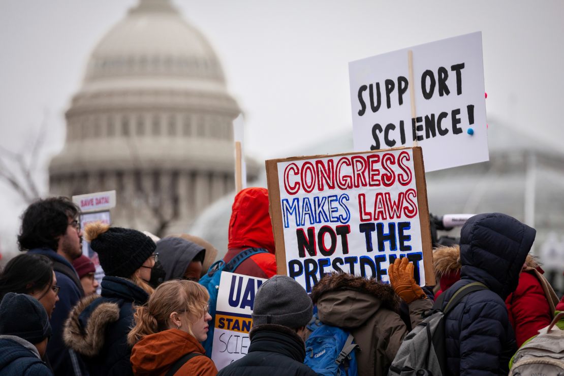 As pessoas participam de uma manifestação contra o congelamento de financiamento de 90 dias do governo Trump e cortes de empregos em agências de saúde em Washington, DC, em 19 de fevereiro de 2025.