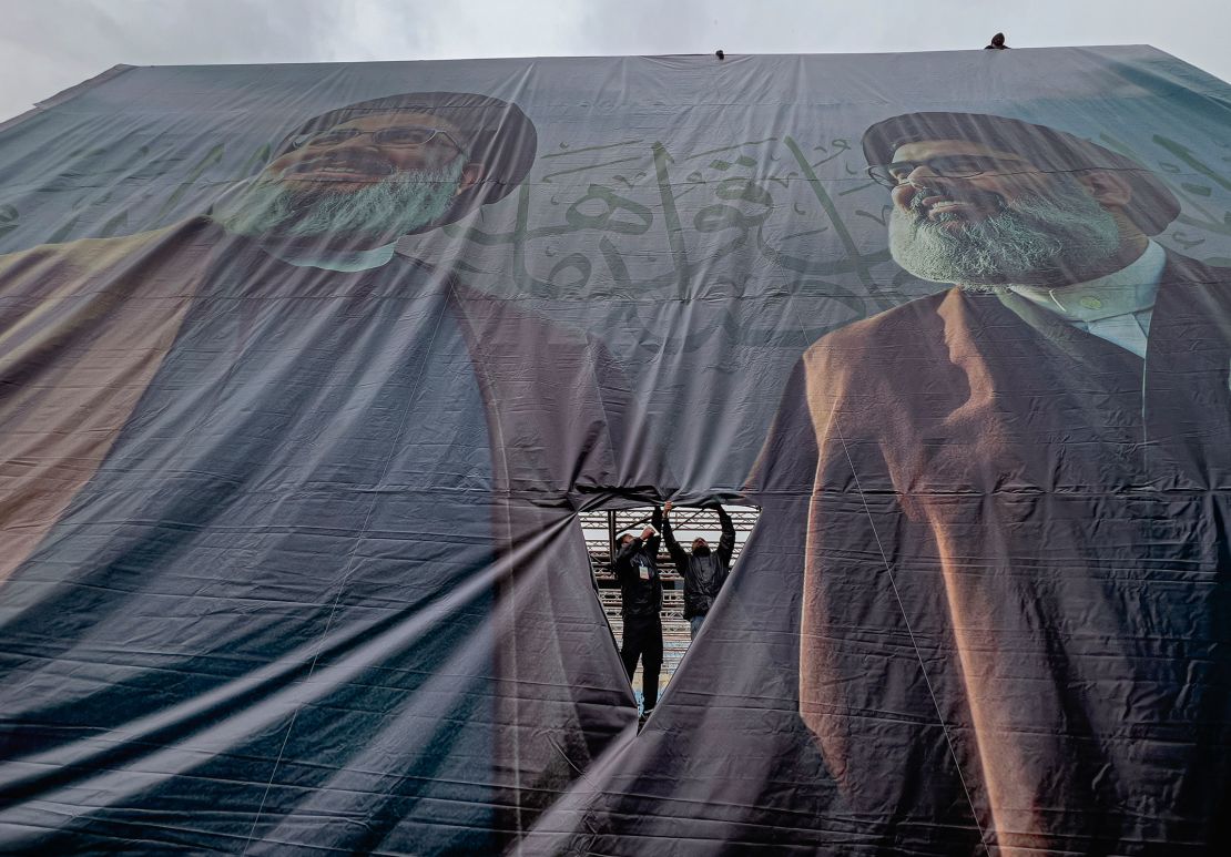 Workers display a giant banner with the portraits of the late Hezbollah leaders Sayyed Hassan Nasrallah, left, and Sayyed Hashem Safieddine.