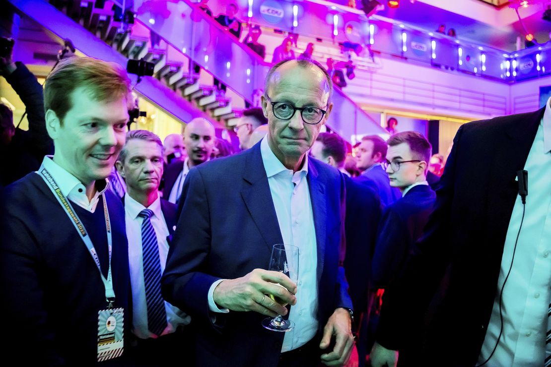 CDU leader Friedrich Merz walks into the party headquarters with a glass of beer in his hand on Sunday.