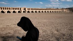 An Iranian man uses his cellphone while standing on the dried-up riverside of the Zayandeh Rud river, with the Si-o-se-pol (33-Bridge) historical bridge visible in the background, in the historic city of Isfahan, Iran, on February 22, 2025. Zayandeh Rud is one of the main tourist attractions of Isfahan, which has completely dried up. Historical bridges such as the 33-Bridge on the river may be damaged due to the subsidence of the Zayandeh Rud riverbed if the drought continues. (Photo by Morteza Nikoubazl/NurPhoto via AP)