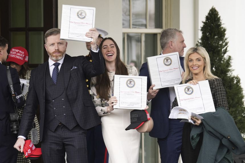 People carrying binders bearing the seal of the US Justice Department reading
