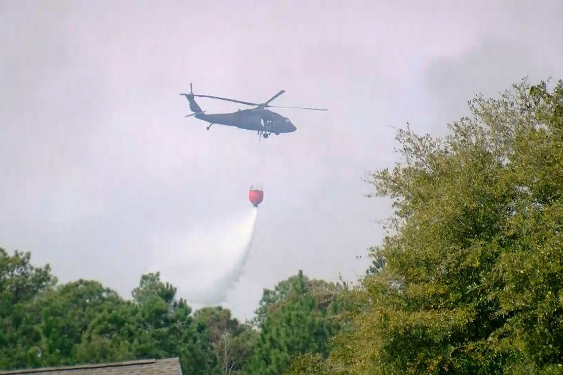 A helicopter drops water to help contain a fire in the Carolina Forest area west of the coastal resort city of Myrtle Beach, South Carolina, Sunday, March 2, 2025.