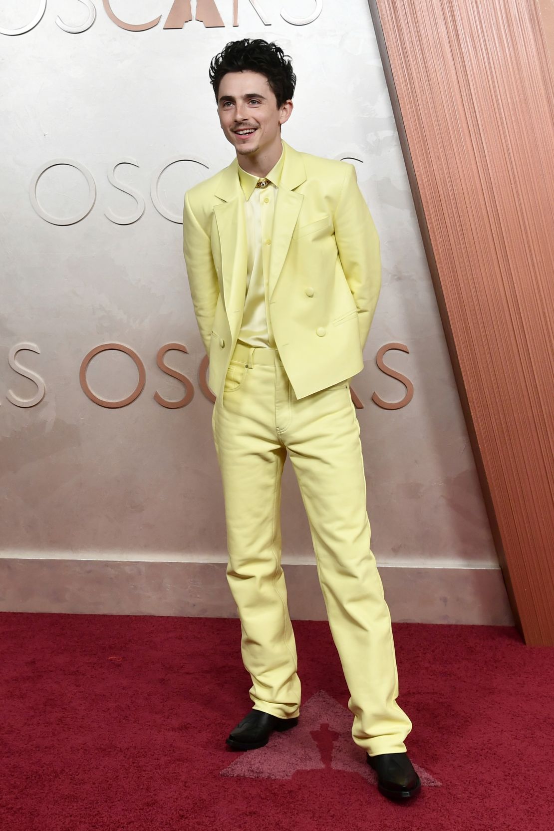 Timothée Chalamet, a Best Actor nominee for “A Complete Unknown,” arrived on the red carpet in a bold butter yellow Givenchy suit, featuring a cropped double-breasted jacket and matching shirt and pants.