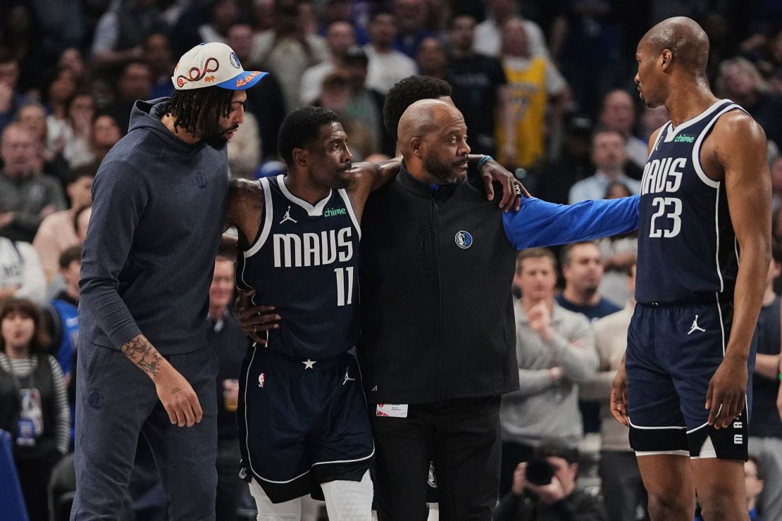 Anthony Davis, left, and a staff member, right, assist Kyrie Irving off the court after he suffered his injury.