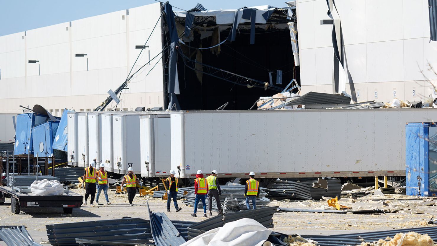 Workers walk outside a damaged warehouse after storms moved through Lewisville, Texas, on March 4.