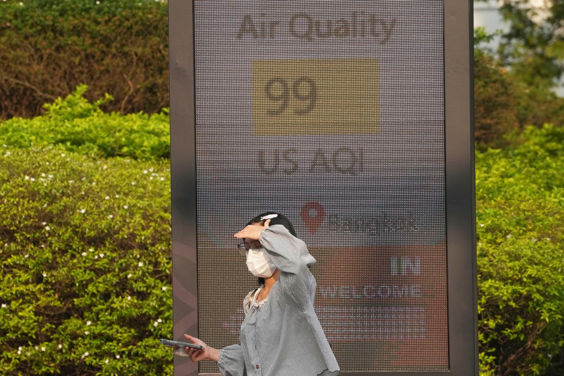 A pedestrian wears a face mask in front of a sign displaying the Air Quality Index in Bangkok, Thailand, on February 6, 2025.