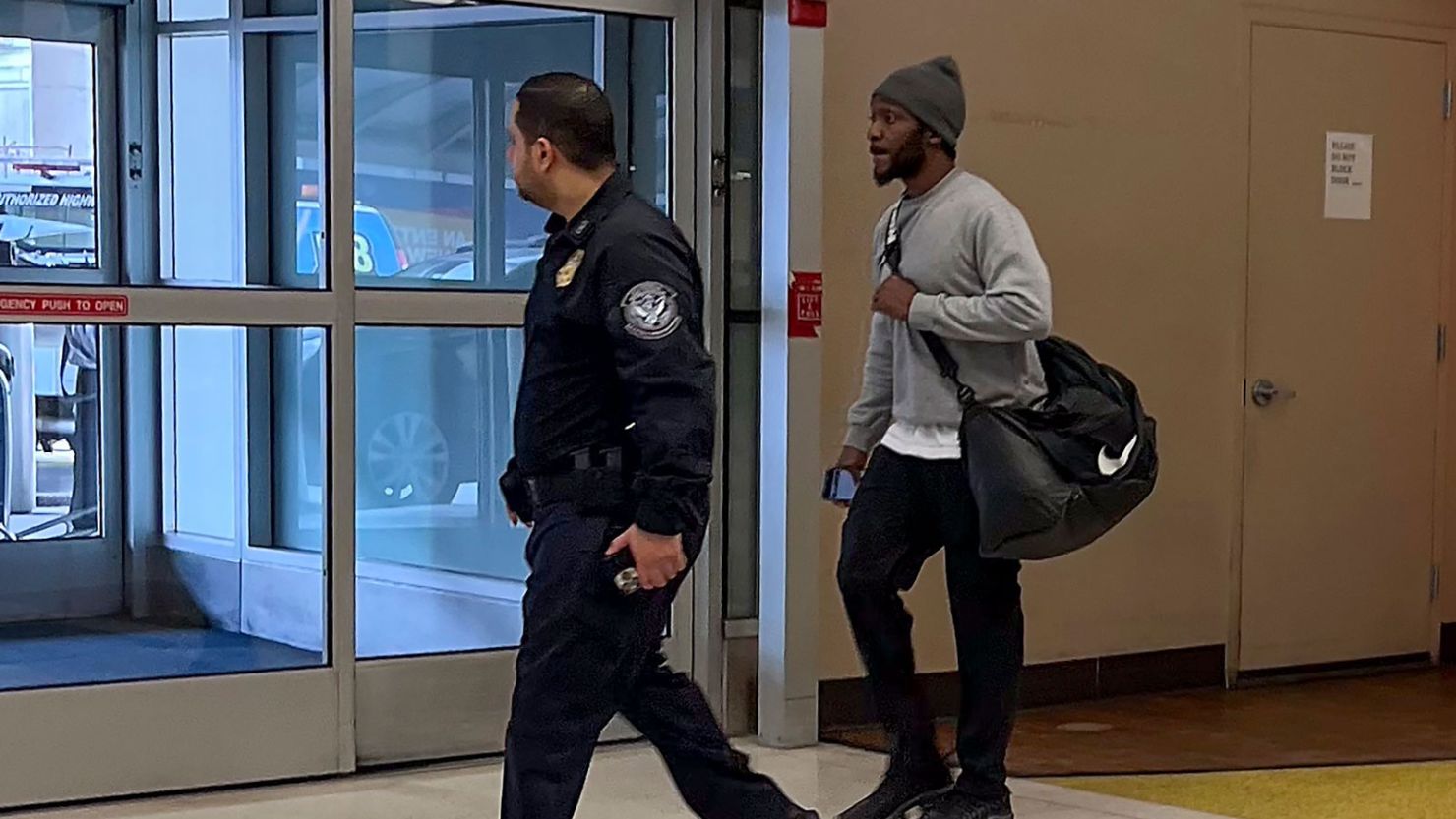 One of the six American prisoners flown from Kuwait to New York on Wednesday, March 12, 2025, right, is escorted by a Customs and Border Protection agent out of Terminal 7 at John F. Kennedy International Airport in New York.