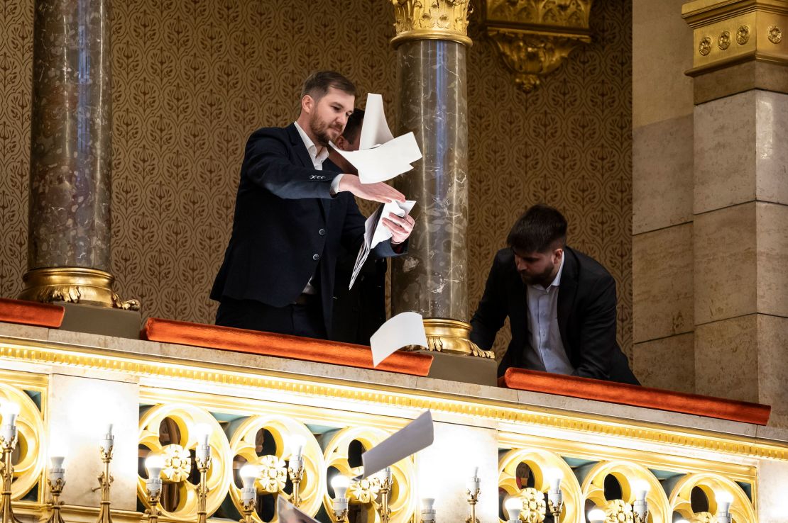 Ferenc Gelencser of Momentum, left, throws pamphlets from the balcony during the plenary session of the Hungarian parliament in Budapest, Hungary, on March 18.