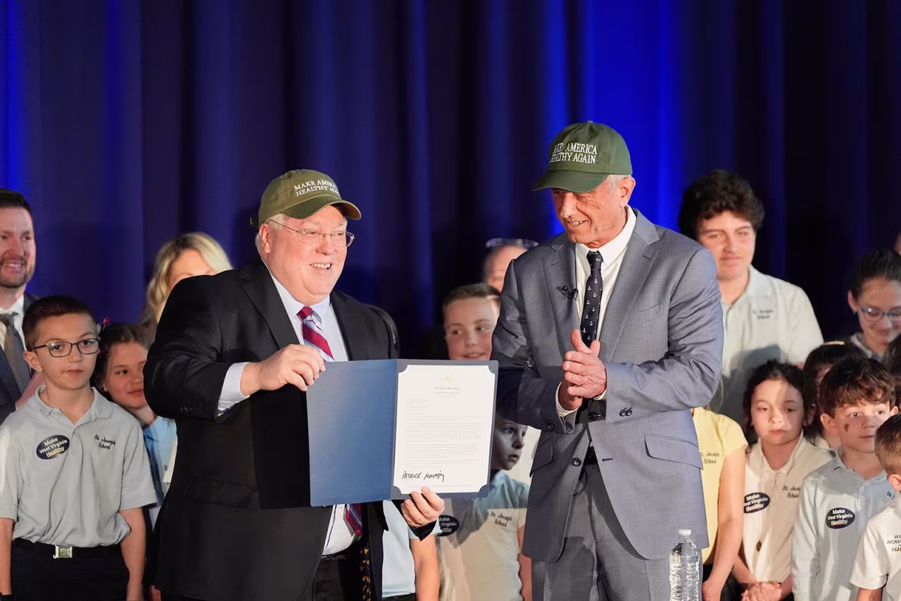 West Virginia Gov. Patrick Morrisey, left, holds a letter of intent to request changes to the state's SNAP and food dye legislation next to Health and Human Services Secretary Robert F. Kennedy Jr., on Friday, in Martinsburg, West Virginia.
