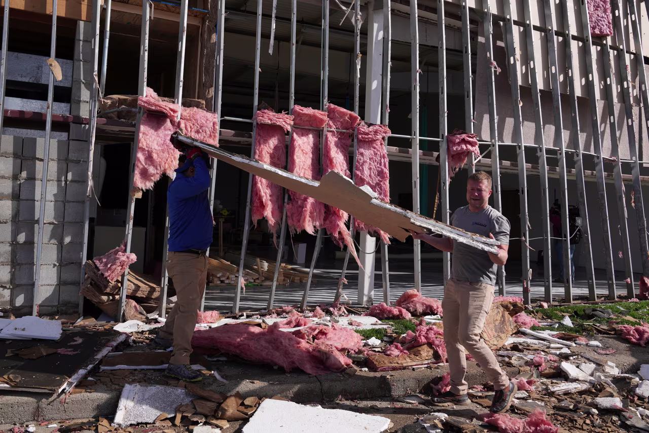 People clean up a damaged warehouse in Carmel, Indiana, on Thursday.