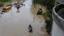 Un niño mira mientras personas recorren en bote una carretera inundada el domingo en Frankfort, Kentucky.