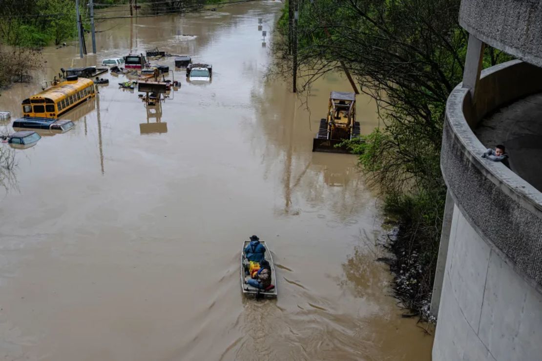 Un niño mira mientras personas recorren en bote una carretera inundada el domingo en Frankfort, Kentucky.