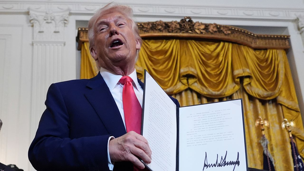 President Donald Trump holds a signed executive order during an event in the East Room of the White House, Tuesday, April 8, 2025, in Washington.
