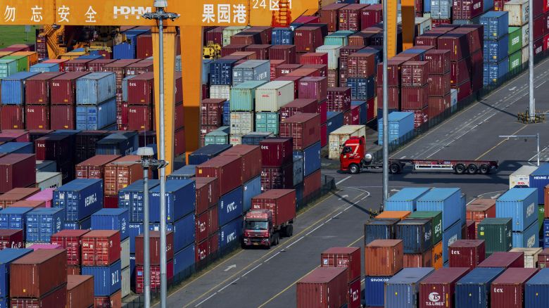 Trucks move amid containers stacked at a container terminal port on the Yangtze River in southwest China's Chongqing municipality.