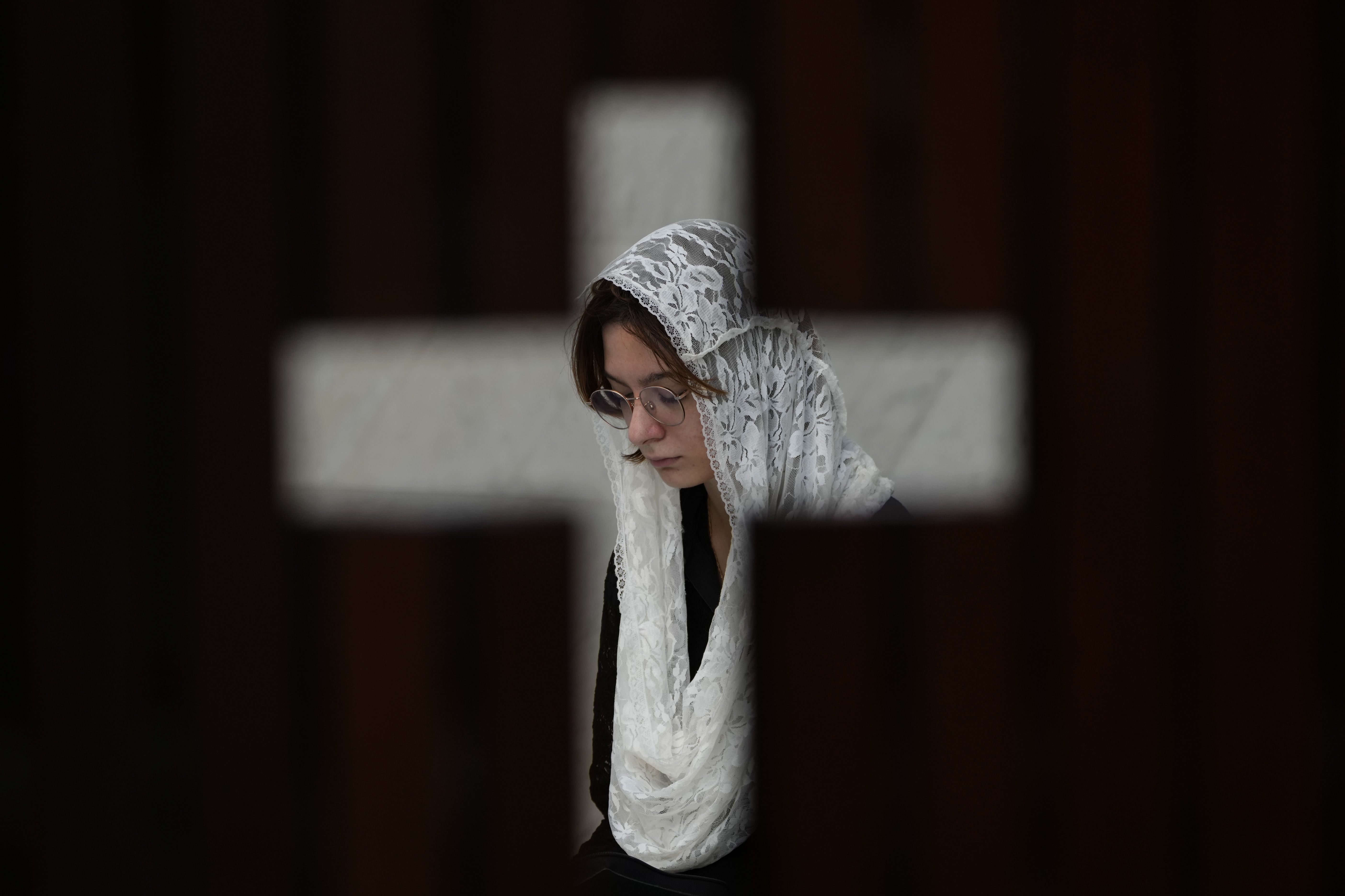 A worshipper, photographed through the door of a confessional, prays during Mass in Brasilia, Brazil.