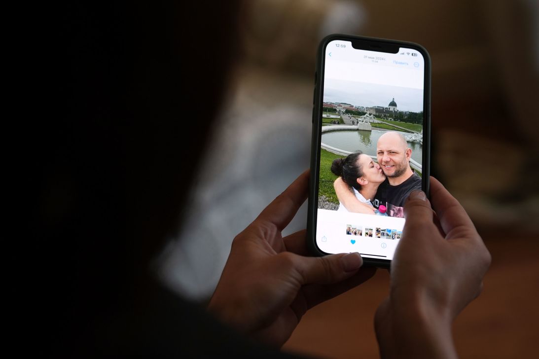 Oksana Tarasiuk holds a cell phone displaying a photo of herself and her husband, Maksym Chernyak.
